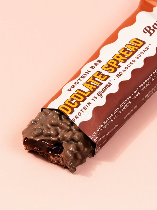 Barebells Chocolate Spread protein bar with orange wrapper showing product name and chocolate coating