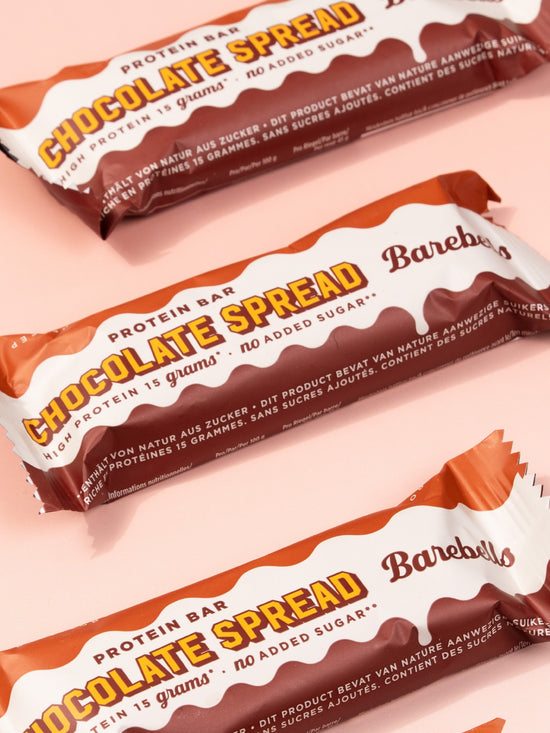 Three Barebells Chocolate Spread protein bars with orange and white packaging displayed diagonally