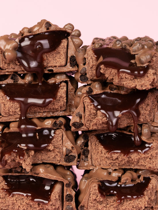 Stacked chocolate cake pieces with chocolate spread and chocolate pearls on top