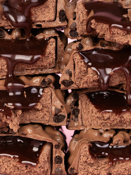 Chocolate spread coating chocolate cake pieces with chocolate pearls and dark crumbs